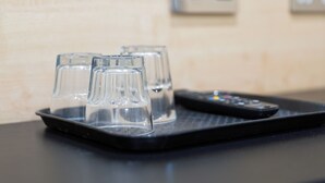 A tray with three glasses and a remote control on a table. - St. George hotel (London)