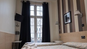 A hotel room with two beds, a TV, a picture on the wall, and a window with curtains. - St. George hotel (London)