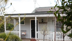 Une maison avec un porche, un petit jardin et des panneaux solaires sur le toit.