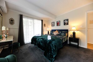 Un dormitorio con cama, mesitas de noche, un escritorio y una silla.