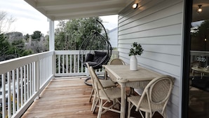 Une terrasse en bois avec des meubles en osier et un fauteuil suspendu.