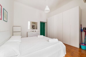 Ein Schlafzimmer mit einem Bett, einem Schminktisch, einem Spiegel, einer grünen Tür und einem Wischmopp.