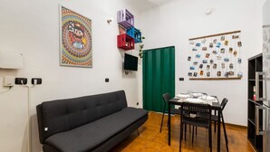 Une pièce comprenant un canapé, une table à manger avec des chaises, une porte verte et un mur orné de photos.