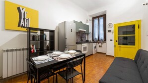 Une cuisine compacte avec une table à manger pour quatre personnes, un canapé et une porte jaune.