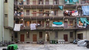 Un immeuble résidentiel à plusieurs étages, doté de balcons, de climatiseurs et d’un espace où sont garés des vélos, situé dans la cour intérieure.