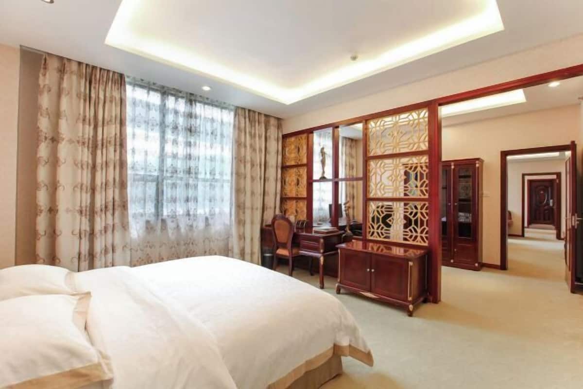 Quarto de hotel com cama, secretária, cadeira, guarda-roupa e um ecrã decorativo.