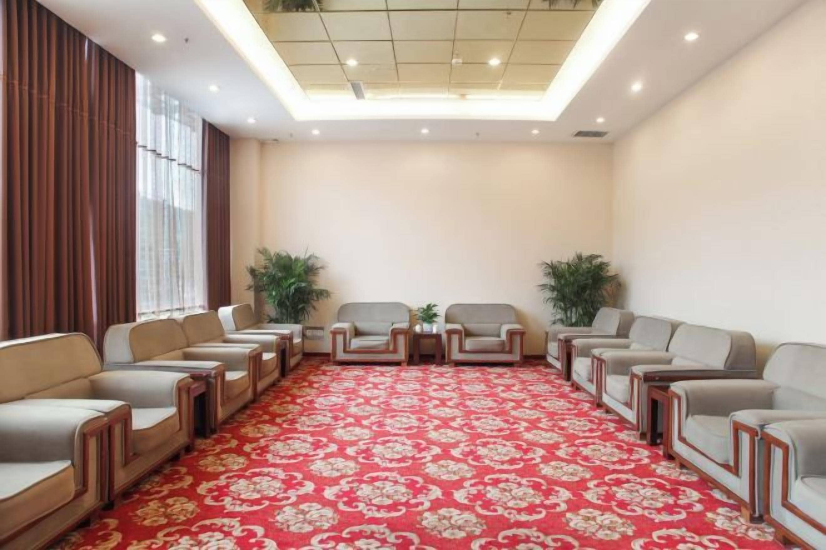 A conference room with a red patterned carpet, rows of chairs, and a ceiling with recessed lighting.