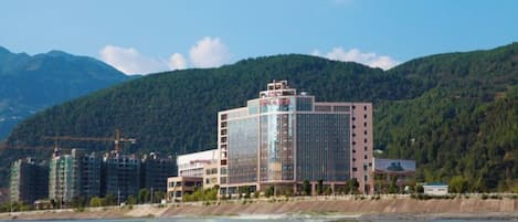 Un hotel de diseño moderno, situado cerca de una masa de agua con montañas al fondo.