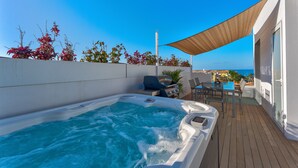 A hot tub on a deck with a view of the sea, a barbecue grill, and outdoor seating. - Green House - modern villa with a private rooftop pool in the south of Tenerife! (Guía de Isora)