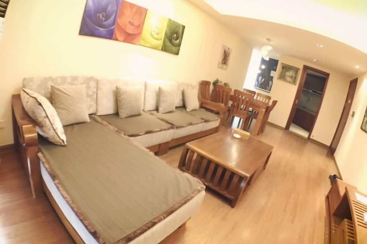 A room with a sofa, a wooden coffee table, and a dining table with chairs.