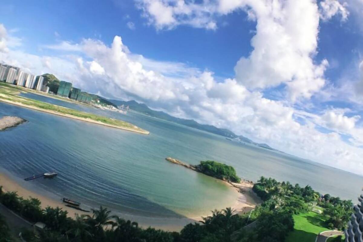 A coastal view with a beach, water, and buildings in the background.