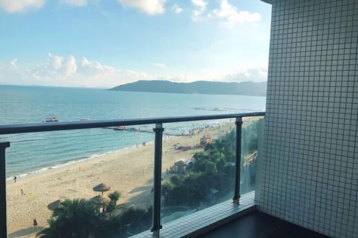 A balcony with a view of a beach and the sea.