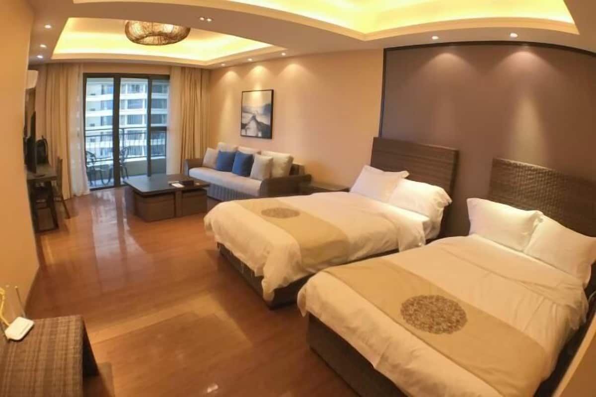 A hotel room with two beds, a sofa, a TV, and a balcony with curtains.