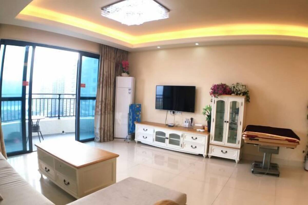 A modern hotel room with a balcony, a flat-screen TV, a cabinet with glass doors, and a billiards table.
