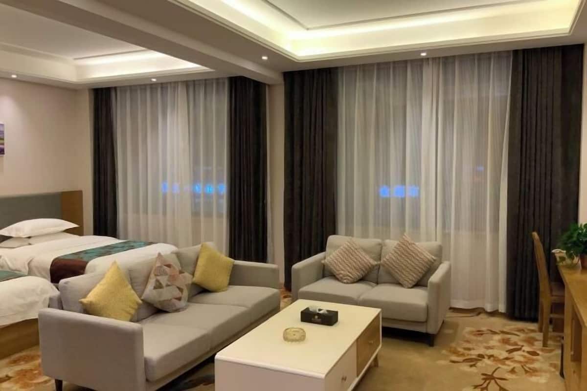 Una habitación de hotel con una cama, dos sofás, una mesa de centro y una mesa de comedor.