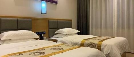 A hotel room with two beds, a headboard, a bedside table, a lamp, and a painting on the wall.
