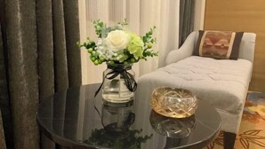 A round table with a vase of flowers and a decorative glass object. - Jinjiaxiang Hotel (Xiji)