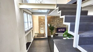 Een modern interieur met een trap, een stenen muur en een Netflix-bord.