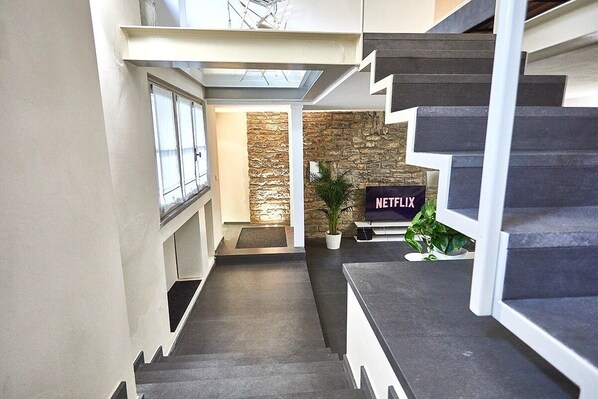A staircase leading to a living area with a stone wall and a Netflix sign.