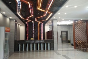 Un área de recepción de diseño moderno, que incluye un mostrador de recepción, una pantalla digital de pared y un revestimiento mural con diseño.