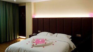 A hotel room with a large bed, a headboard, and a bedside table with a phone. - Hengxi Boutique Hotel (Dahua)