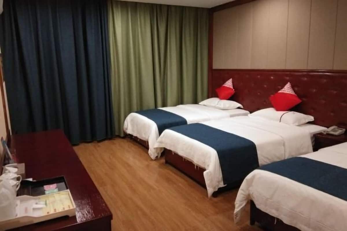 A hotel room with two beds, a wooden desk, and a green curtain.