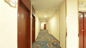 A hotel hallway with patterned carpet, wooden doors, and a sign indicating room number 8401. - Hengxi Boutique Hotel (Dahua)