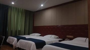 Habitación de hotel con tres camas, cabecera de madera y una cortina a un lado.