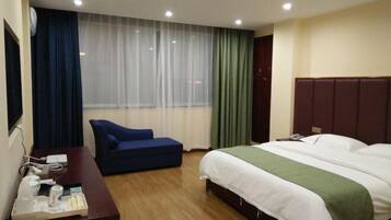 Habitación de hotel con cama, escritorio, silla, ventana con cortinas y televisión.