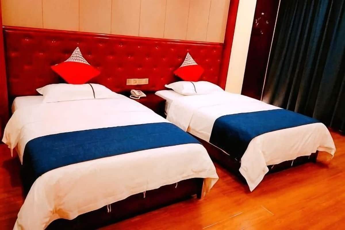 Two beds with red headboards, white bedding, and a wooden floor.