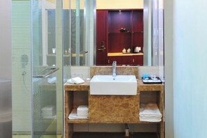 A bathroom with a glass shower enclosure, a sink with a marble countertop, and a mirror above the sink. - Wenhai Hotel (Ma'anshan)