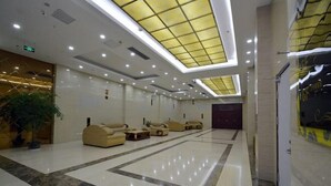 A spacious lobby with a high ceiling, recessed lighting, and a central seating area with sofas. - Wenhai Hotel (Ma'anshan)