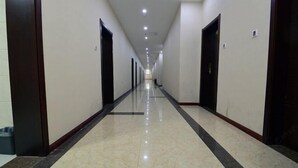 A long, narrow hallway with doors on both sides, leading to rooms. The floor is tiled, and the walls are plain. - Wenhai Hotel (Ma'anshan)