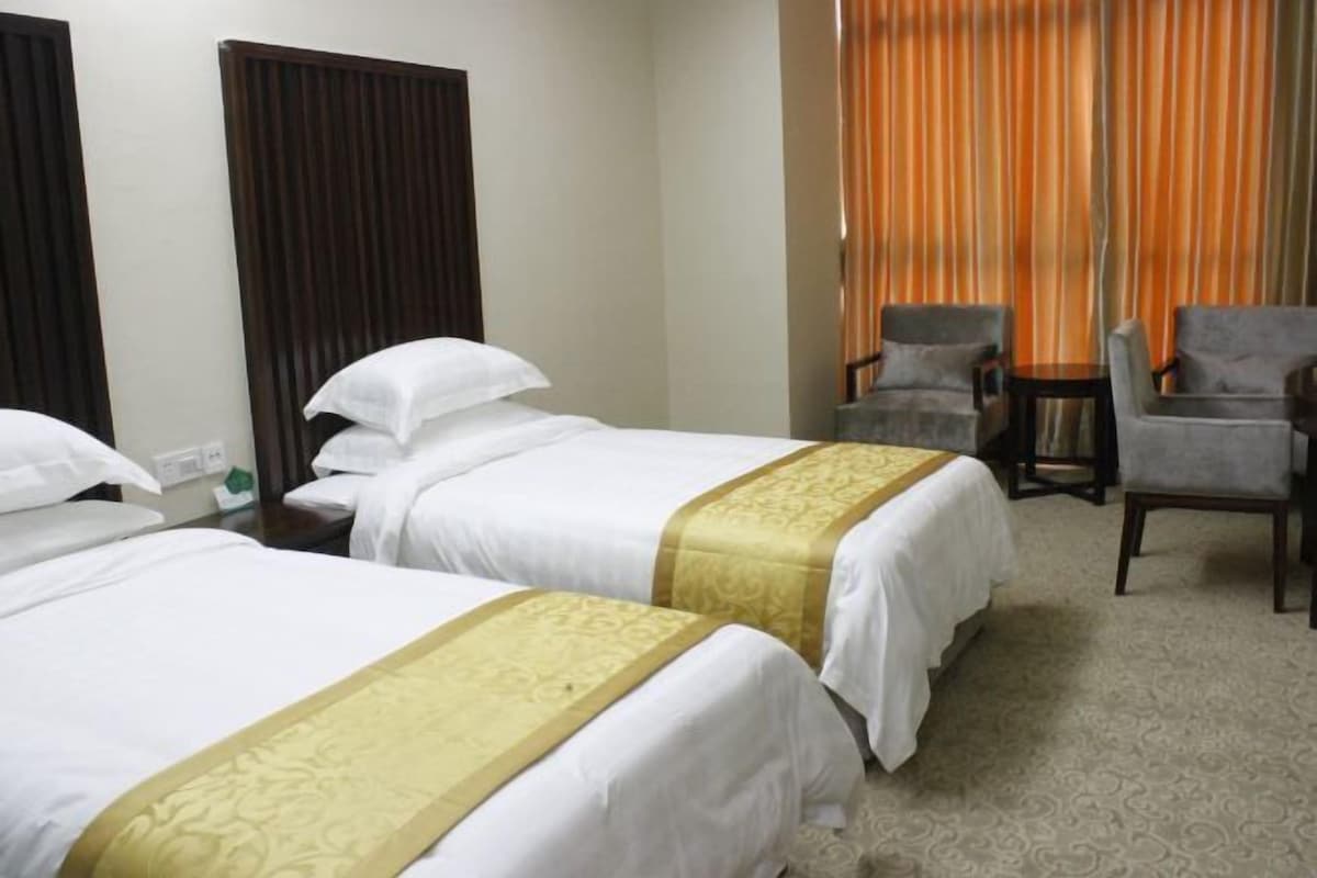 A hotel room with two beds, a desk, and two armchairs.
