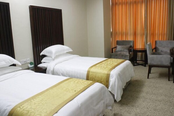 A hotel room with two beds, a desk, and two armchairs. - Wenhai Hotel (Ma'anshan)