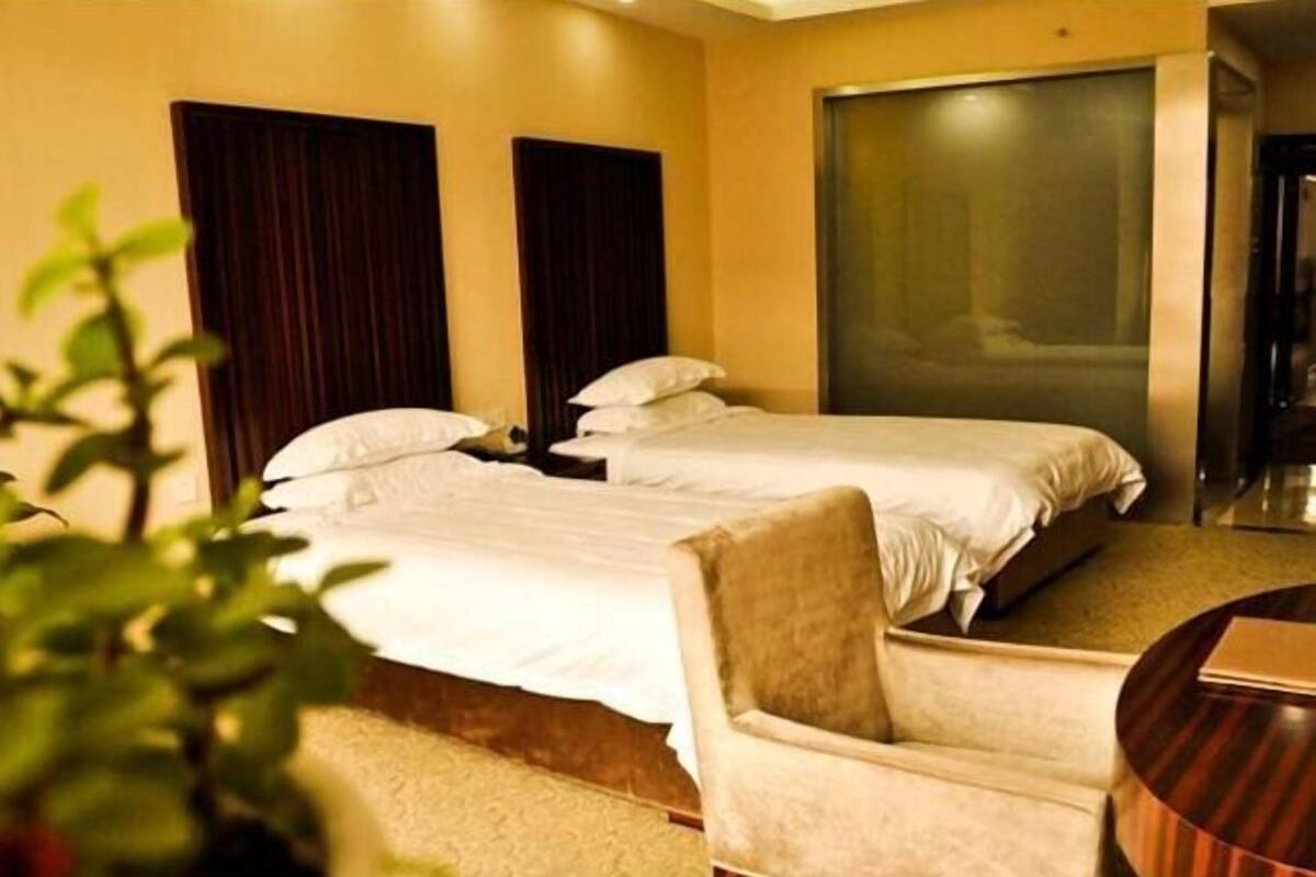 Una habitación de hotel con dos camas, una silla y una mesita.