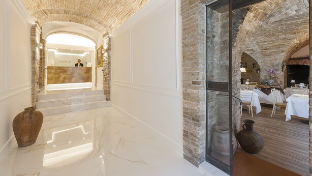 A hotel lobby with a stone ceiling, marble floors, and a reception desk. - Asisium Boutique Hotel (Assisi)