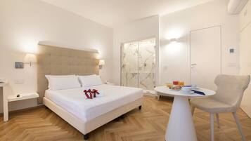 Une chambre d’hôtel moderne, dotée d’un grand lit, de tables de chevet, d’une petite table ronde avec une chaise et d’un espace douche.