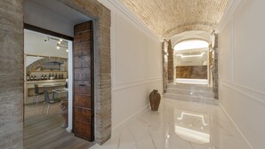 A hallway with a brick wall, a wooden door, and a marble floor. - Asisium Boutique Hotel (Assisi)