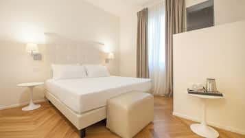 Quarto de hotel com uma cama grande, mesas de cabeceira, uma televisão de tela plana e uma pequena mesa com bandeja.