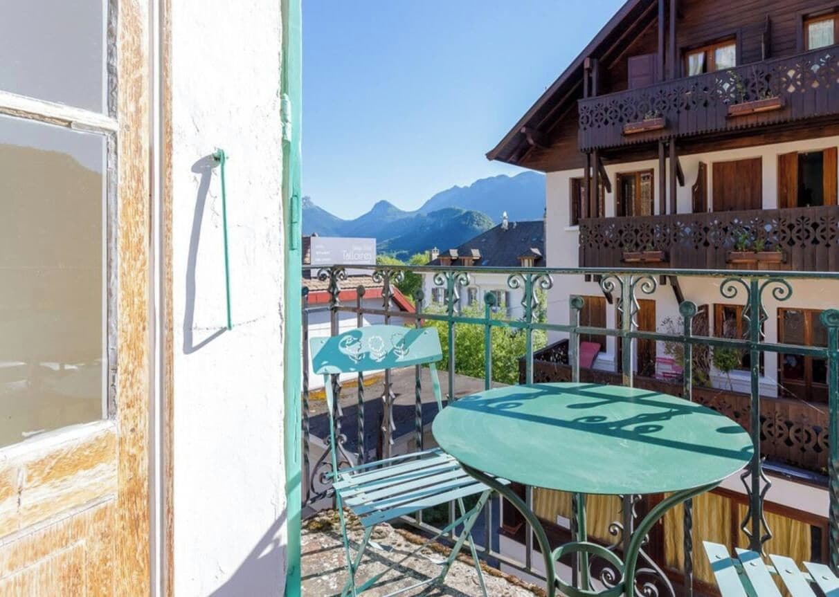 Ein Balkon mit Tisch und Stühlen mit Blick auf eine gebirgige Landschaft.