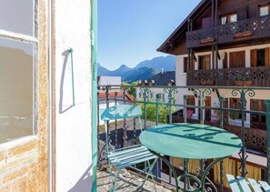 Ein Balkon mit Tisch und Stühlen mit Blick auf eine gebirgige Landschaft.