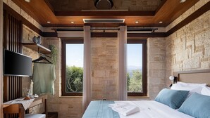 A bedroom with a large bed, a desk, and a TV. - Villa Peacock with Spa Facilities (Chania)