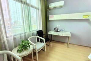 A room with a desk, two chairs, a potted plant, and a view through large windows. - Huayuan Fashion Hotel 338 (Xiaochang)
