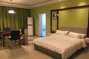 Une chambre d’hôtel équipée d’un lit, d’un bureau, de chaises, d’un réfrigérateur et d’une porte donnant sur une autre pièce.