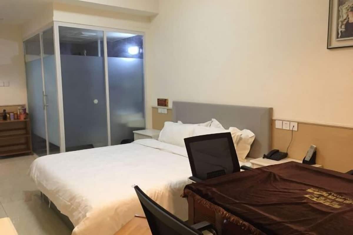 Ein Hotelzimmer mit Bett, Schreibtisch mit Stuhl, Kleiderschrank und Nachttisch mit Telefon.