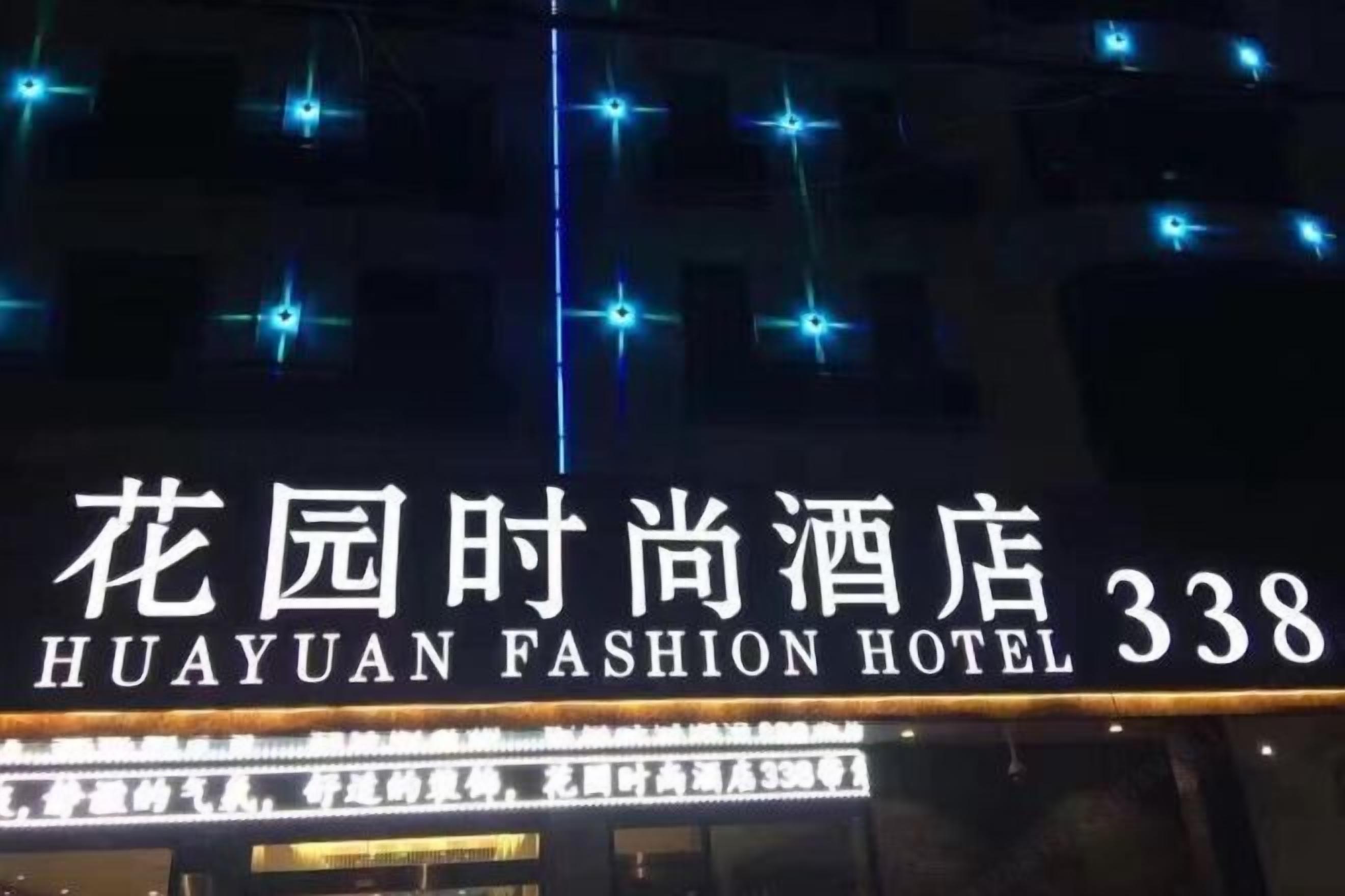 Exterior del Hotel Huayuan Fashion con señalización iluminada y luces decorativas.