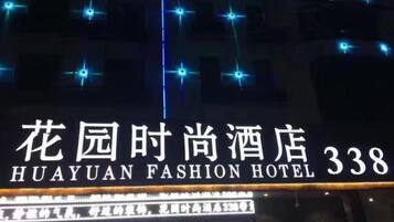 Exterior del Hotel Huayuan Fashion con señalización iluminada y luces decorativas.