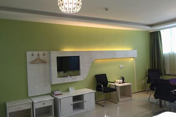 Une chambre d’hôtel équipée d’un téléviseur à écran plat fixé au mur blanc, d’un bureau avec une chaise, d’une petite table avec une chaise et d’un lit.