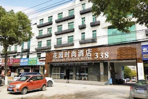 Un hôtel dont la façade porte une enseigne indiquant « Flower Garden Fashion Hotel 338 ».
